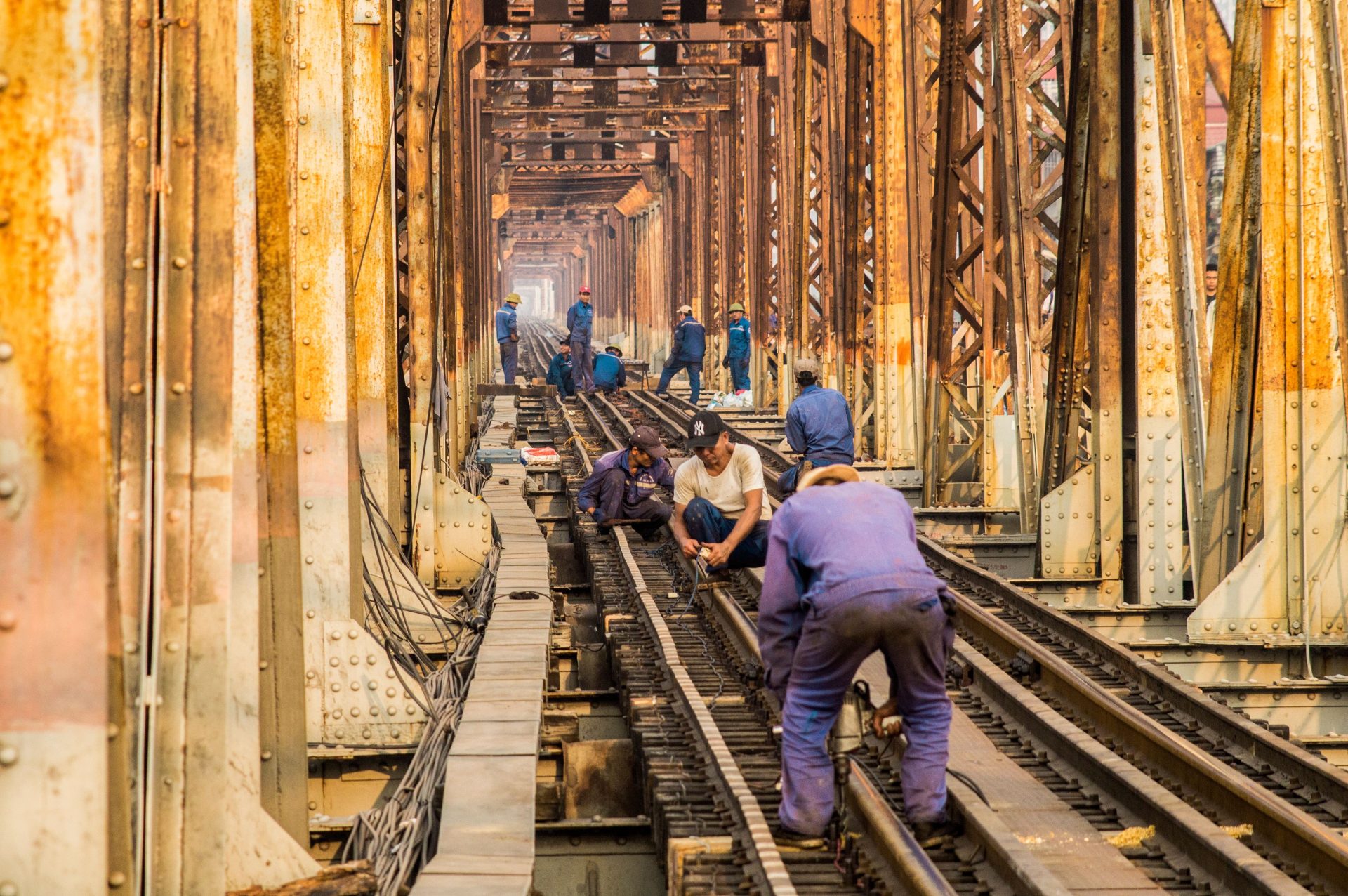 Gruppe anonymer männlicher Techniker in schmutzigen Uniformen, die gemeinsam in der Stadt eine Eisenbahnstrecke bauen