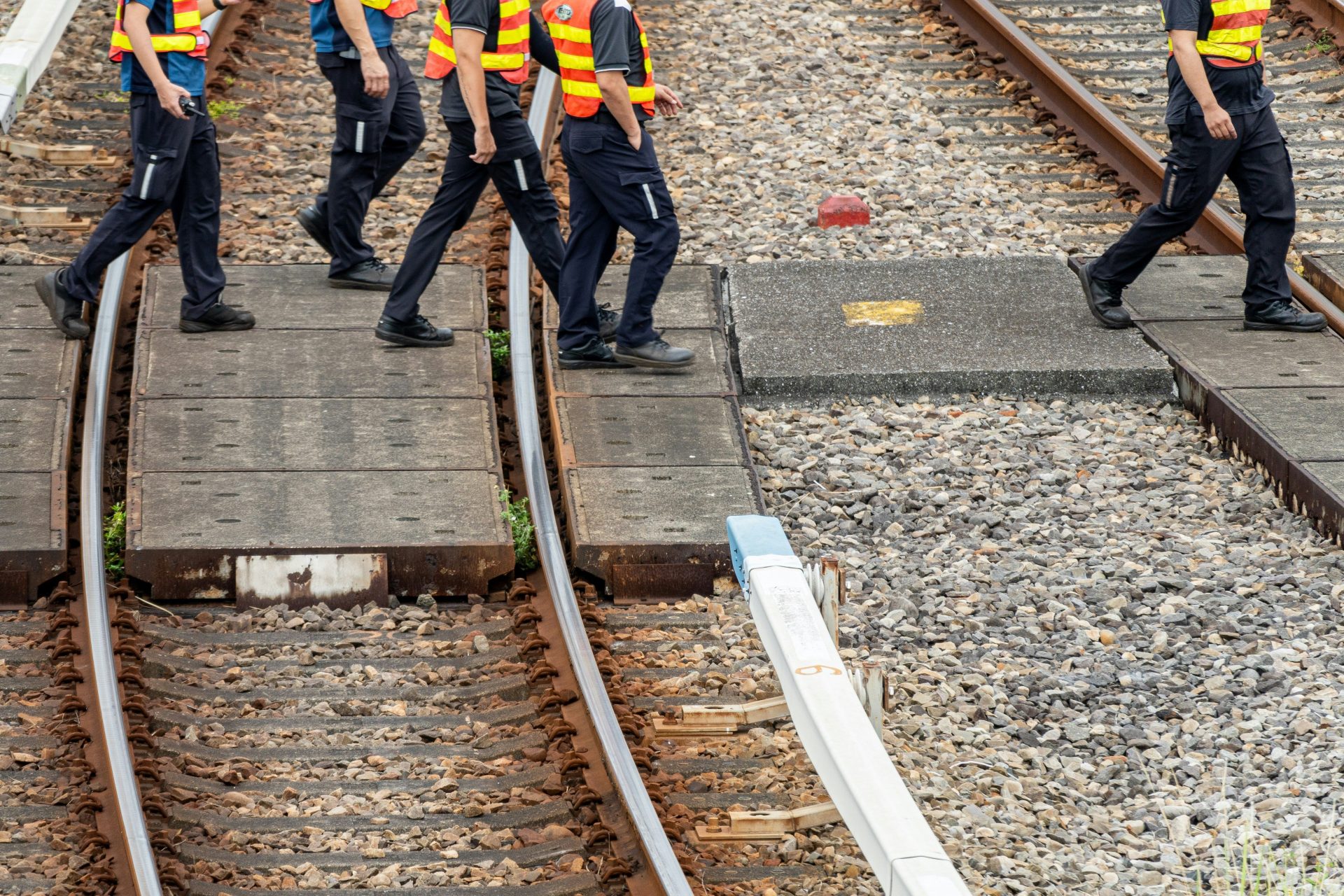 Menschen in Warnwesten gehen über Bahngleise.